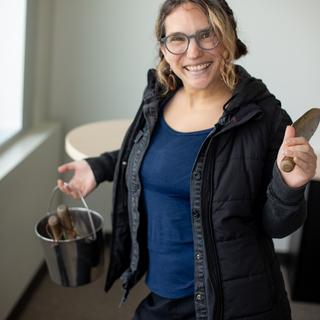 A woman smiling holding gardening tools